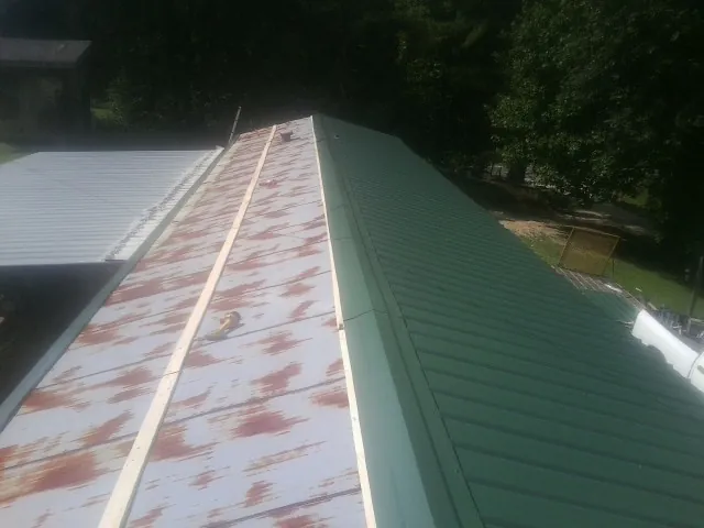Old rusted panels beside newly installed green metal roofing — Wind Damage Roof Repair by Roofing Brothers in Cheney