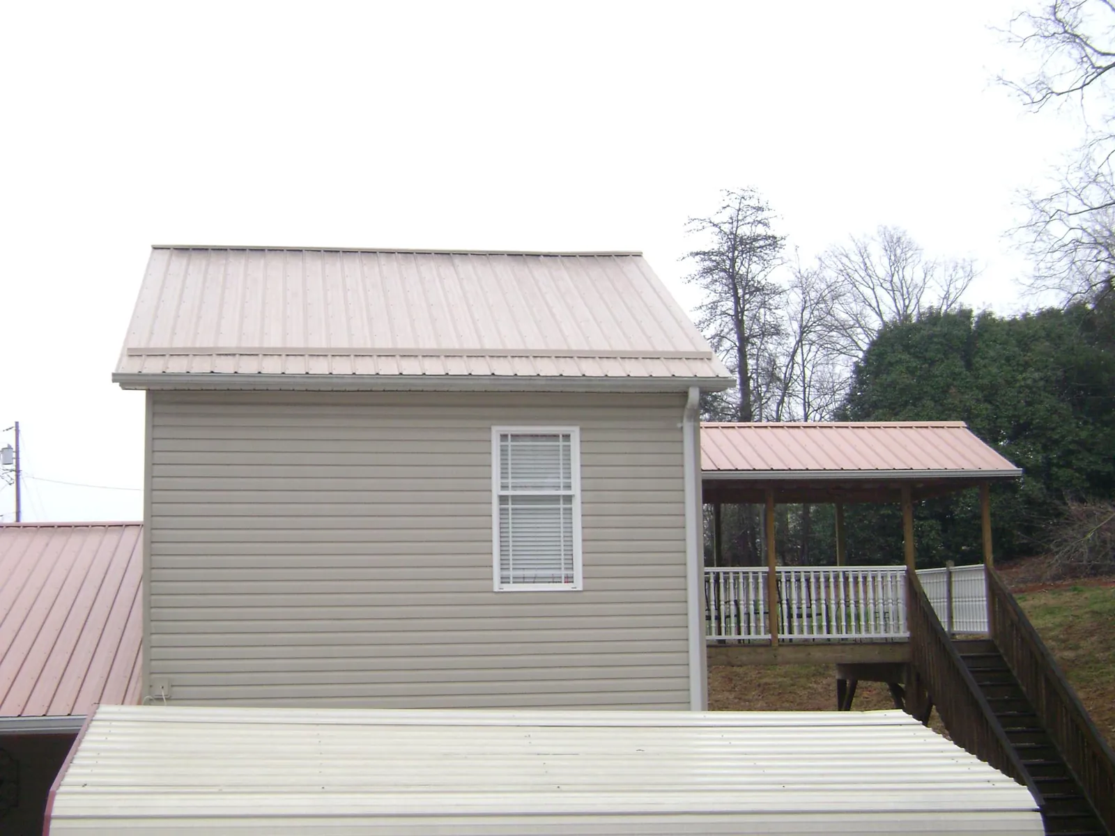 Tan metal roofs on a two story addition and attached porch, from a Roof Replacement job in Cheney